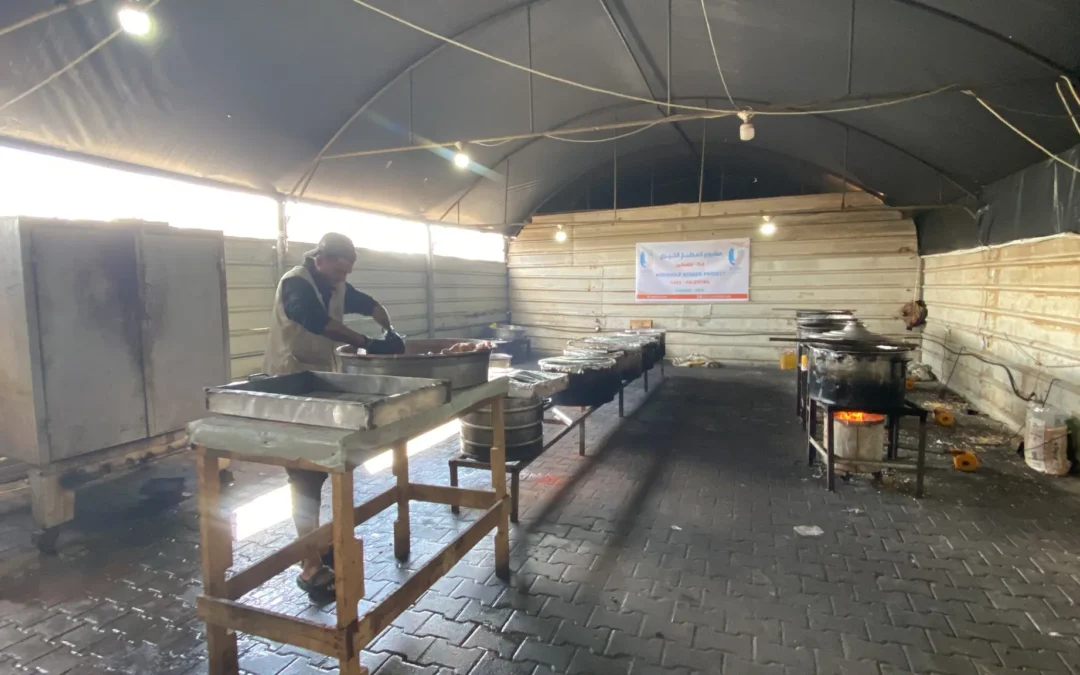 Man bereidt voedsel in een grote kookruimte als onderdeel van een humanitair Aqiqah-project in Gaza