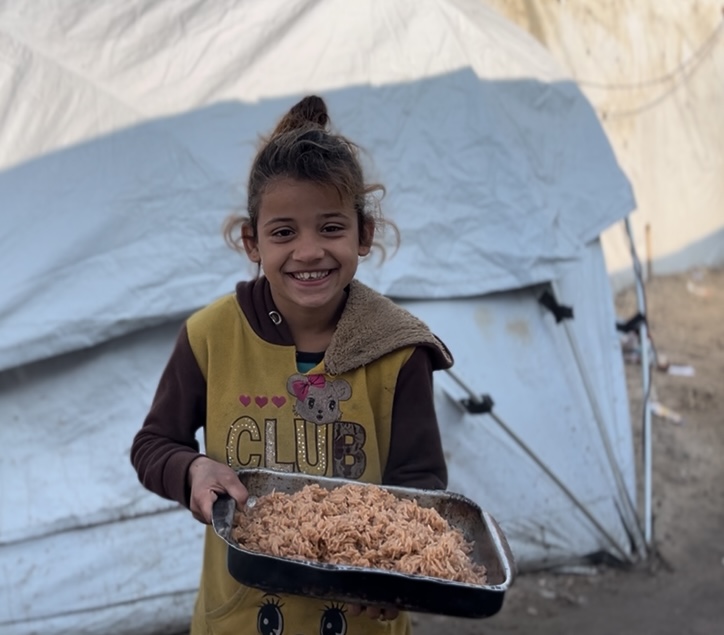 Lachend Palestijns jongetje toont versgebakken brood voor zijn tent in Gaza